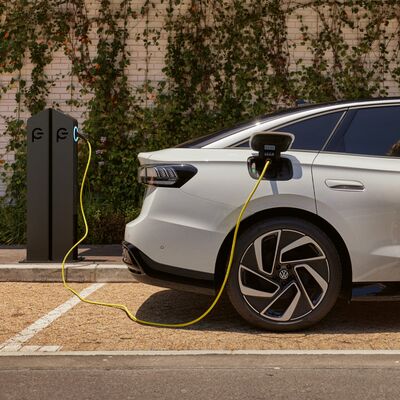 Ein weißes Elektroauto von Volkswagen wird an einer Ladestation aufgeladen. | Škoda Auto Röhr.