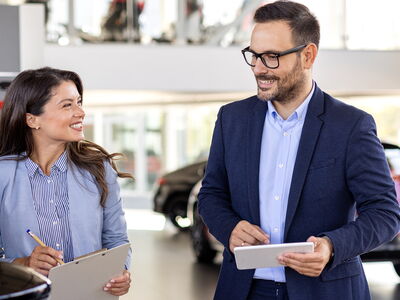 Ein lächelndes Teammitglied der Erich Röhr GmbH & Co. KG berät einen Kunden im Volkswagen Zentrum Passau.